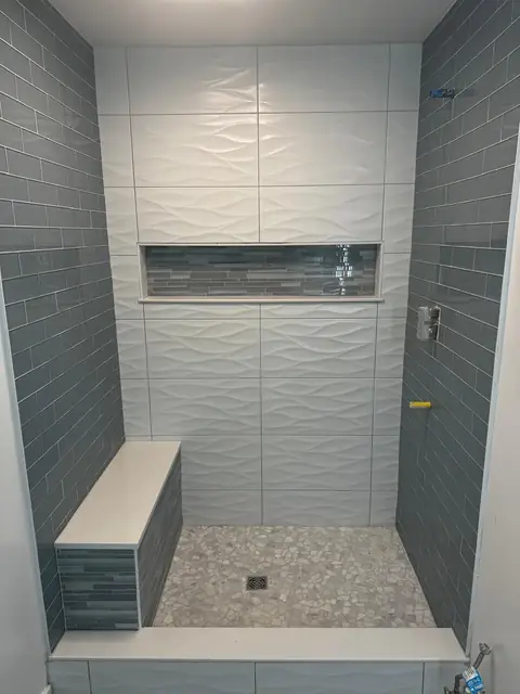 Custom tiled walk-in shower with bench, wall niche and pebble floor