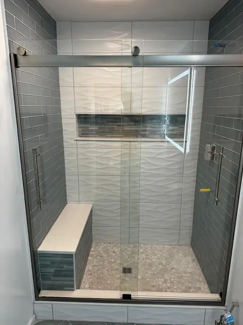 Tiled shower with bench, blue glass tile accent wall and sliding glass door