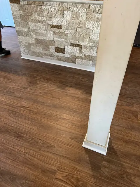 Wood-look flooring installed next to a stacked stone wall