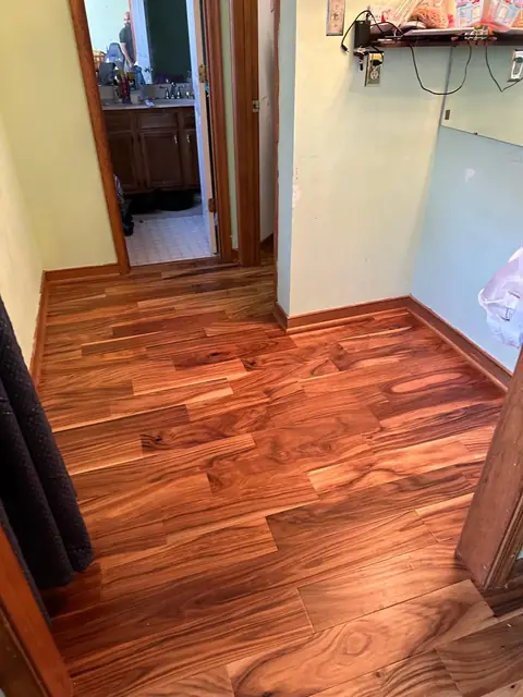 Wood flooring in a hallway leading to a bathroom